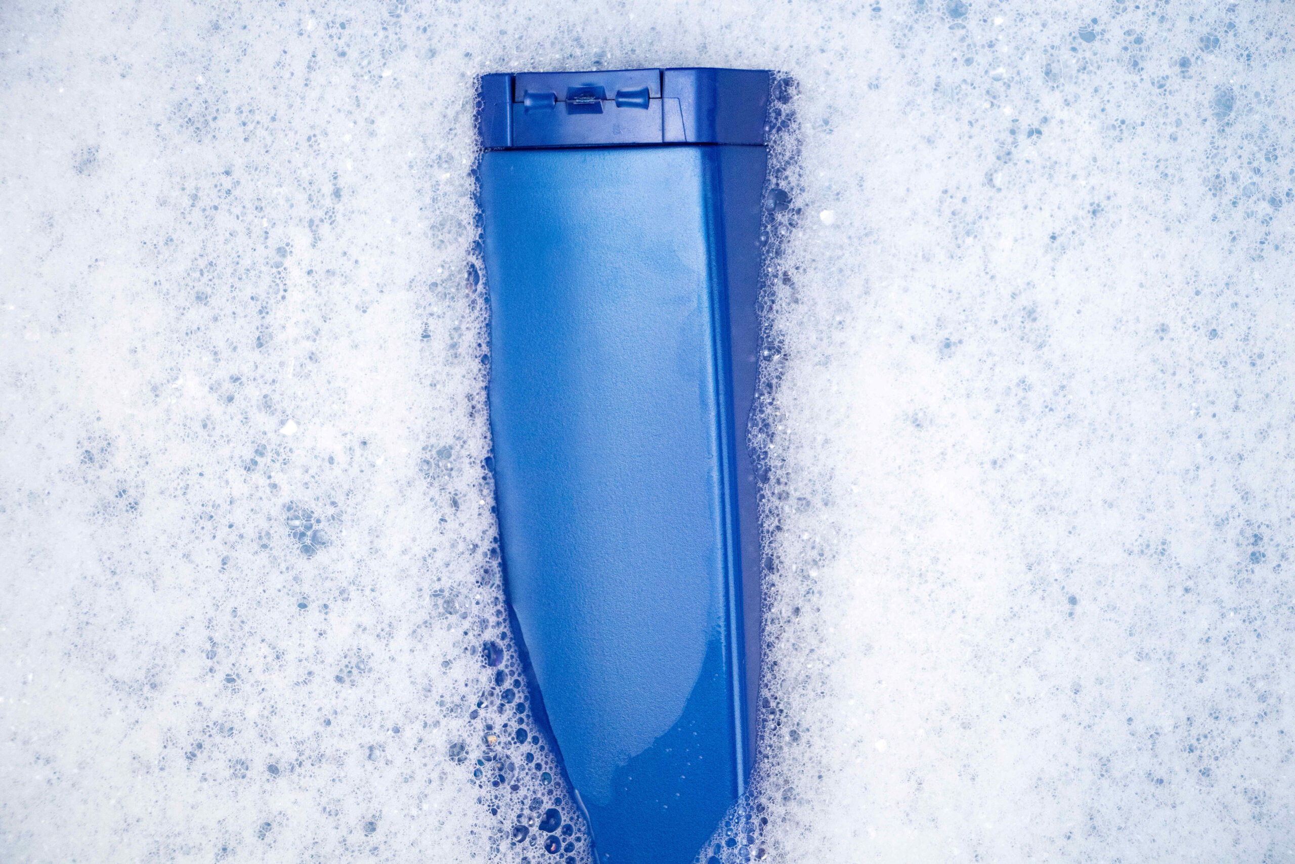 a-blue-can-of-shampoo-floats-in-foamy-water-the