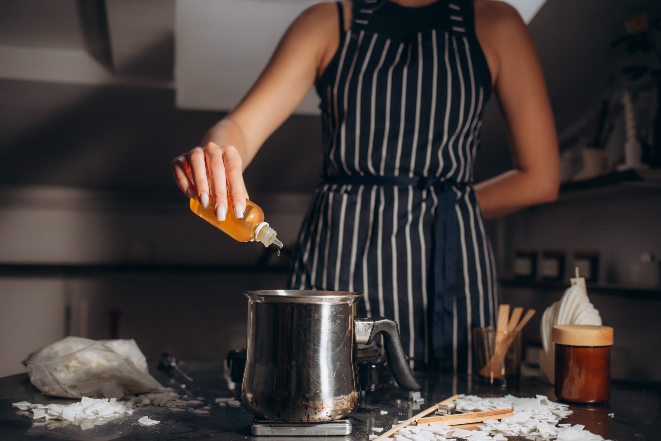 the-woman-adds-flavoring-agent-to-candle-wax